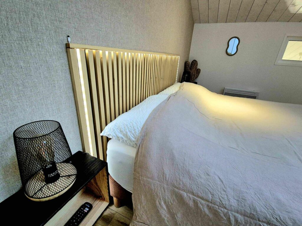Zoom sur la tête de lit en bois avec éclairage led intégré et table de chevet minimaliste noire