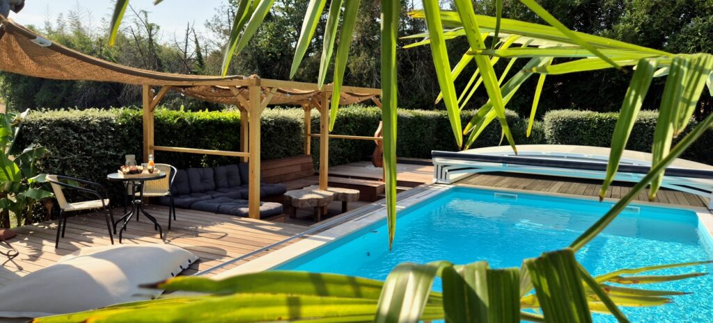 Gros plan sur une feuille de palmier surplombant une piscine avec un pouf géant