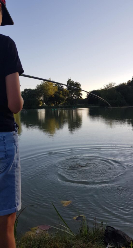 Une personne pêchant tranquillement au bord d'un étang au crépuscule