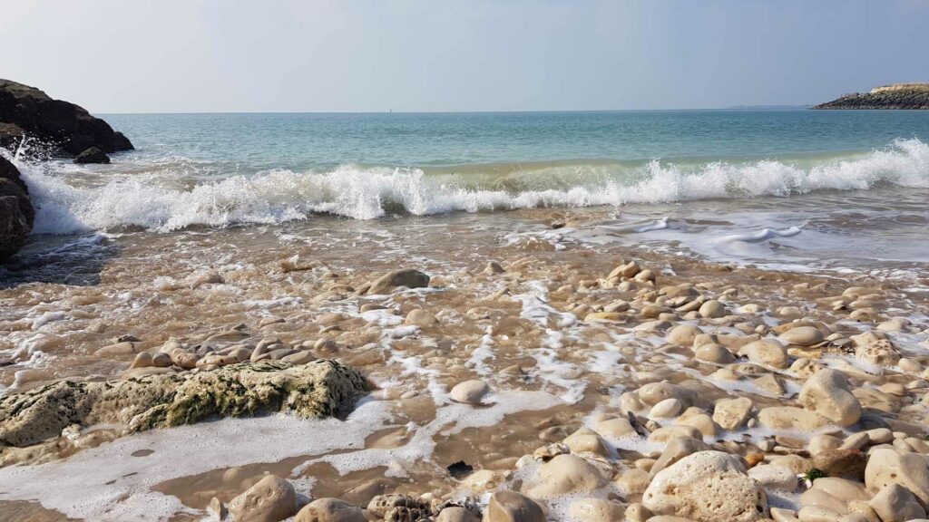 Plage sauvage parsemée de gros galets blancs au bord de l'Océan Atlantique par une journée ensoleillée