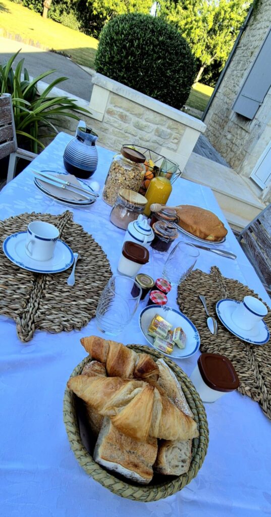 Gros plan sur un panier de croissants frais, gâteau maison et jus d'orange sur une nappe blanche