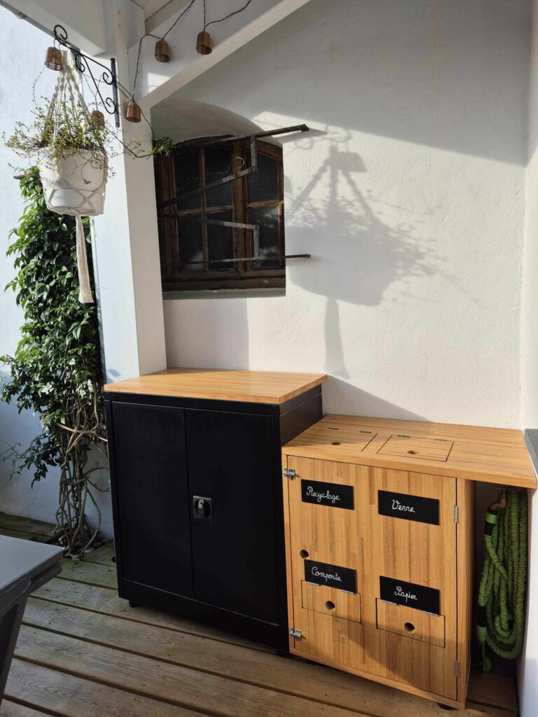 Meuble de tri sélectif en bois sur une terrasse en bois, avec compartiments pour recyclage, verre, composte et papier