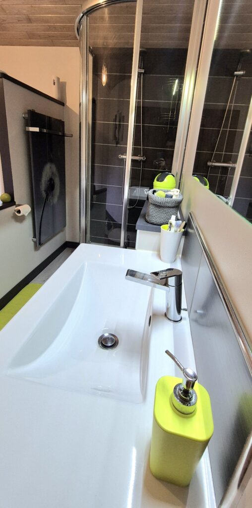 Vasque blanche design avec robinetterie chromée et accessoires de toilettes colorés vert pomme